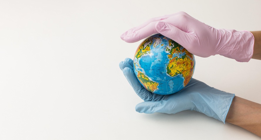 Ręce w rękawiczkach ochronnych trzymające glob ziemski — symbol ekologicznego podejścia do sprzątania